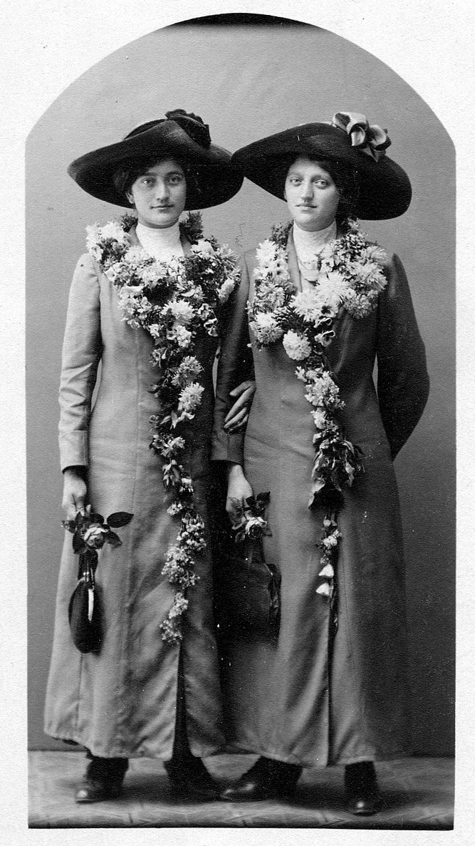 Bild på två systrar iklädda kappa och hatt