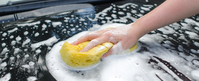 Bilden föreställer hand som tvättar bilen med en svamp